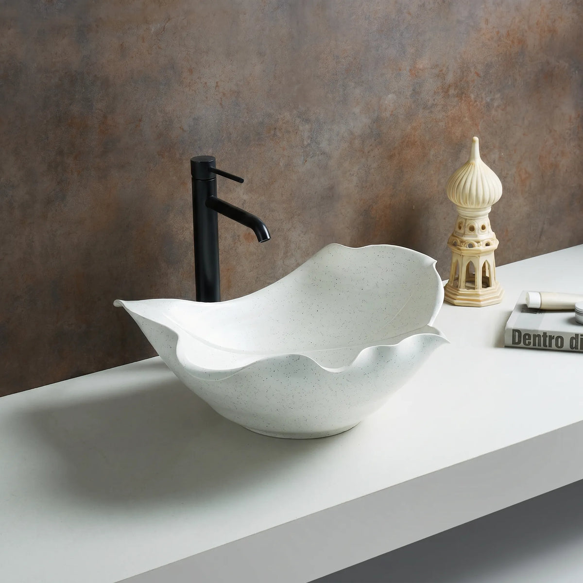White ceramic sink with black faucet on a gray countertop against a brown wall.